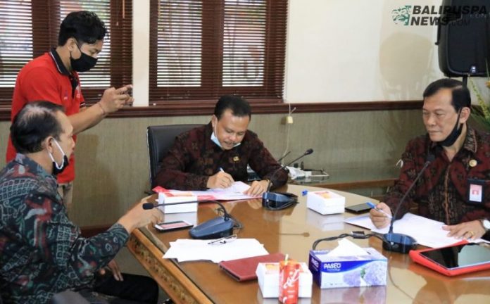 Sekda Provinsi Bali Dewa Made Indra saat menandatangani naskah perjanjian kerja sama dengan Chief Executive Officer (CEO) Mbiz Rizal Paramarta yang dilakukan secara virtual melalui teleconference, Jumat (10/7).