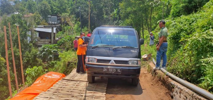 Mobil saat melewati ruas jalan Kabupaten di Desa Sekumpul yang telah diperbaiki sementara, Jumat (19/3/2021)