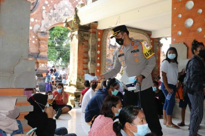Kapolres Tabanan membagikan masker kepada peserta vaksin di Gedung Mario