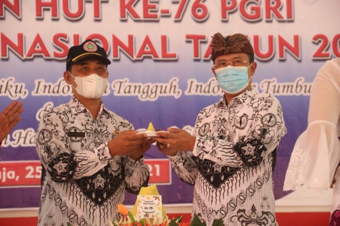 Sekda Gede Suyasa saat menyerahkan potongan tumpeng pada peringatan Hari PGRI dan Guru Nasional, di SMAN Bali Mandara