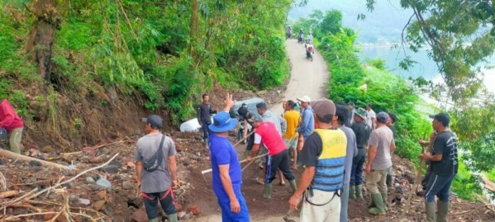 Nampak petugas dan warga gotong royong membersihkan material longsor yang menutup badan jalan