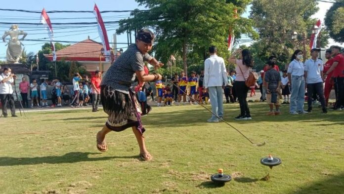Salah seorang anak dari Desa Gobleg, Kecamatan Banjar, Buleleng saat sedang melempar gangsing di permainan tradisional menggangsingan
