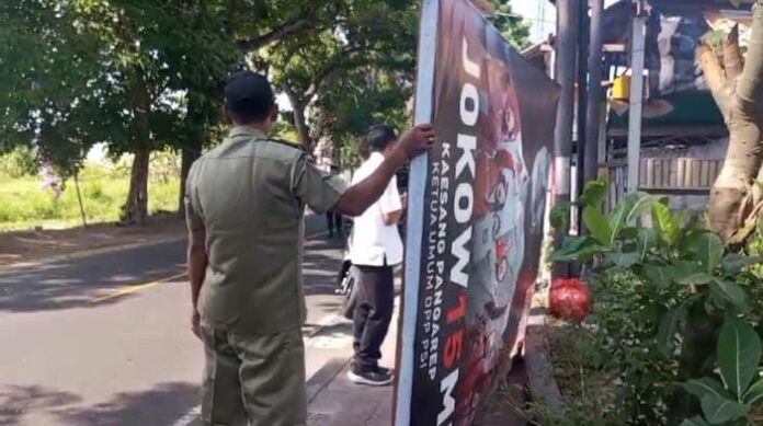 Satpol PP saat menurunkan salah satu baliho di Karangasem