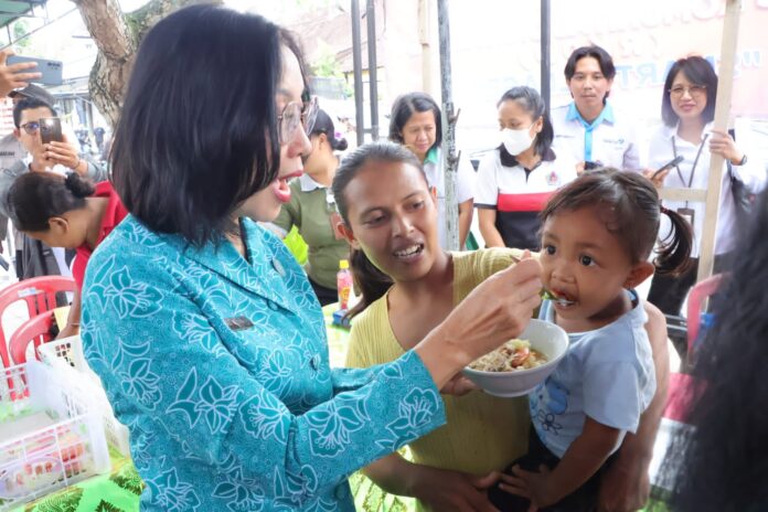 Ny. drg. Ida Mahendra Jaya Menyuapi Balita Makanan Saat Sosialisasi Kegiatan Gerakan Memasyarakatkan Makan Ikan (GEMARIKAN) di Bali, Desa Nyalian, Kecamatan Banjarangkan, Kabupaten Klungkung, Rabu (9/10/2024)