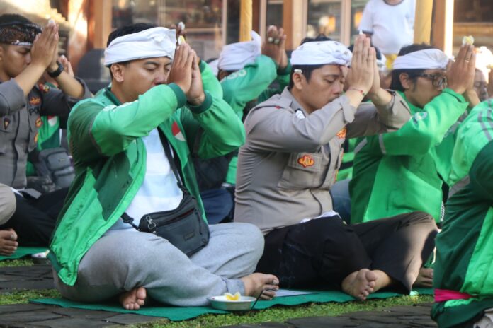 Personel Polri bersama para driver ojol yang beragama hindu menggelar doa bersama di Pura Linggarcana Polda Bali, Selasa (2/9/2025)