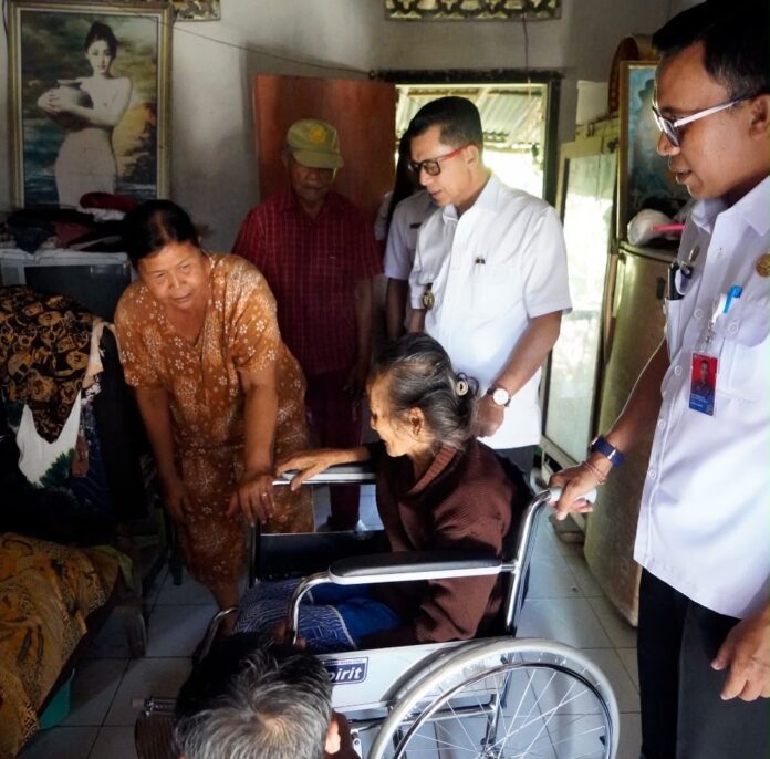 Bupati Klungkung, I Made Satria saat menyerahkan bantuan kursi roda dan sembako kepada lansia di Klungkung